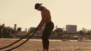 Homem musculoso brincando na praia