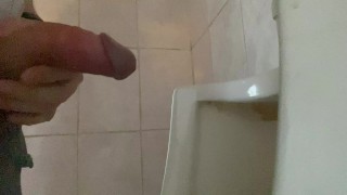 Mit einem großen Schwanz mit großen Eiern auf einer öffentlichen Toilette in ein Urinal gepisst