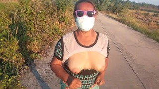 Auntie walks and shows off her breasts on the side of the road.