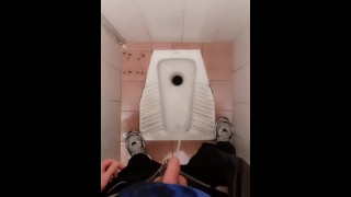 Молодой парень писает в общественном туалете