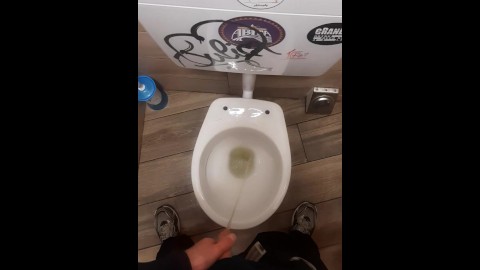 Joven meando en el baño de un bar