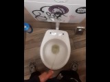 Young man pissing in a bar toilette