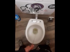 Young man pissing in a bar toilette