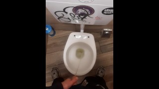 Jonge man pist in een bar toilet