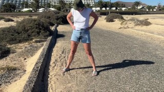 Mädchen pisst in Jeans auf der Straße in der Öffentlichkeit