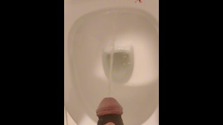 Chico asiático orinando en el baño