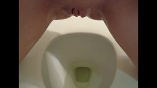 Chatte chauve huileuse dégoulinant de pipi dans les toilettes