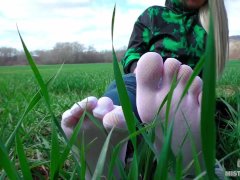 Goddess Feet in cute white socks with jeans on the spring grass field