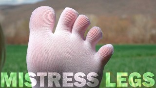 Goddess Feet in cute white socks with jeans on the spring grass field