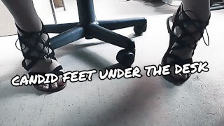 POV viendo los pies de T en sandalias debajo de su escritorio