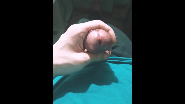 Guy in a blue T-shirt jerks off his dick while sitting in an armchair