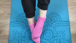 Fitness dívka dělá cvičení na podložce v ponožkách a dává footjob svému trenérovi s cumem na nohou