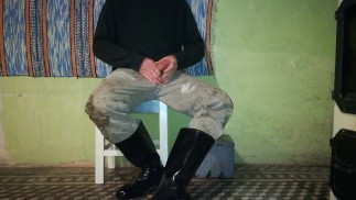 Фермер заботится о своих резиновых сапогах в конце дня