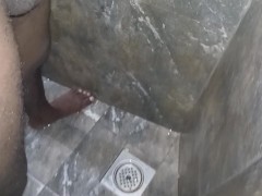 The boy is peeing in the bathroom