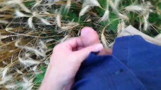 Фермер показывает свои грязные резиновые сапоги и сильно мочится на пшеничном поле