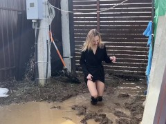 A fashionista in high-heeled boots climbed into a huge dirty pit with mud and water
