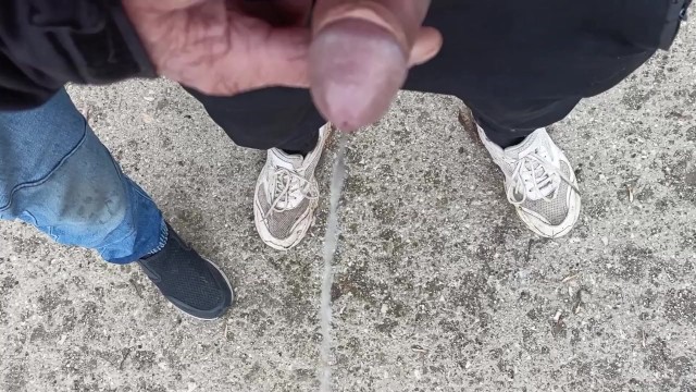 Friend is holding my cock while im peeing on the ground outdoor