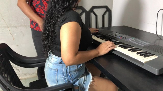 Una joven con curvas y una falda ajustada tomando su primera lección de teclado