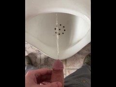 Peeing in a urinal in a men's public restroom