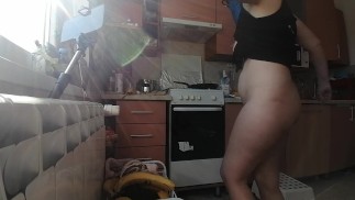 Sexy naked wife prepares food in the kitchen.
