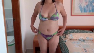 Beautiful мачеха на пляже красуется в бикини и трогает себя.